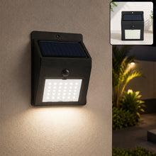 Black solar-powered wall light with 30 LEDs illuminating a beige wall at night, with an inset showing it on a dark wall.