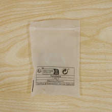 A translucent plastic bag with recycling information printed on it, lying flat on a light wooden surface.
