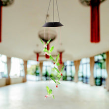 Decorative solar powered hummingbird wind chime hanging in garden