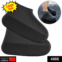 A person's legs and feet, wearing black silicone shoe covers, stand on a wet wooden deck.