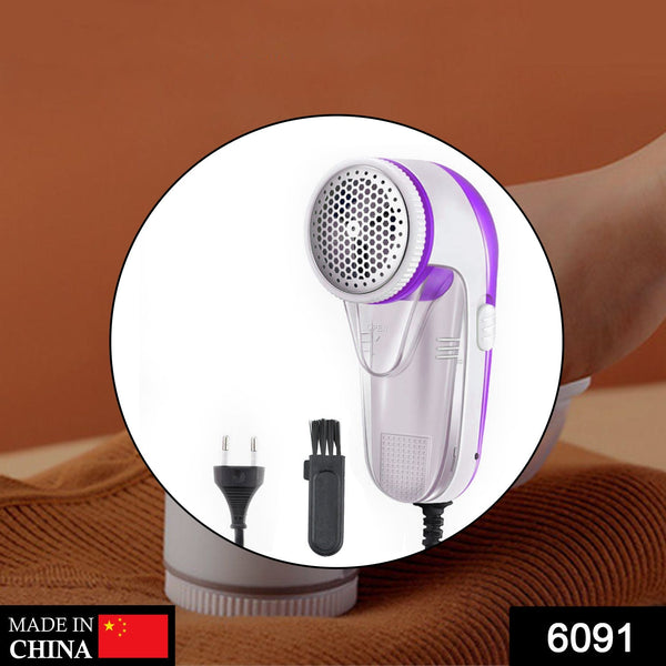White and purple corded lint remover with a cleaning brush and power plug shown in a circular cutout.