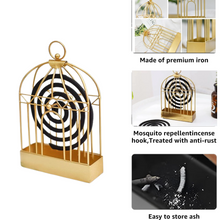 A lit mosquito coil safely burning inside the decorative birdcage holder.