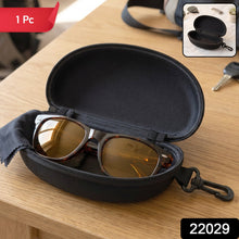 An open black hard shell sunglasses case with brown sunglasses and a black cleaning cloth inside, on a wooden table