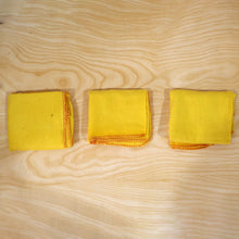 Actual photograph of three folded yellow cotton dusters