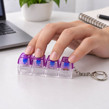 A hand presses down on the four purple and clear keyboard switches of a keychain on a white desk.