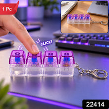 A hand presses a purple and clear four-key keyboard switch keychain, with a smaller inset image on a desk and a 