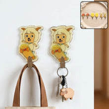 Two cartoon sheep on skateboards, acting as wall hooks, with a bag and keys hanging from them.