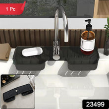A black silicone faucet splash guard with a bar of soap and a pump bottle on a white kitchen sink, with a red 