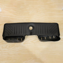 A black silicone faucet splash guard with drainage grooves and two side compartments, lying flat on a light wood surface.