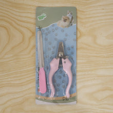 Pink pet nail clipper and filer set in blister packaging on a light wooden background.