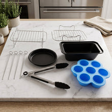 A complete set of air fryer accessories on a white marble counter, including two metal racks, four skewers, a black round