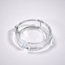 Clear glass ashtray featuring a classic round shape and convenient cigarette slots.