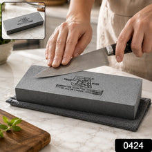 A gray silicon carbide whetstone with black text rests on a gray towel on a white marble counter.