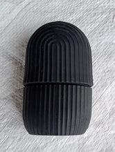 Black face ice roller placed on a textured grey cloth, showing its sleek design.