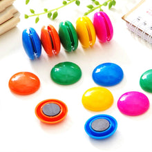 Circular board magnets in assorted colors displayed on a surface.
