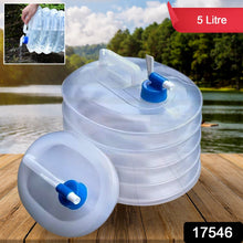 A translucent collapsible water container with a blue spigot sits next to its collapsed form on a wooden surface by a lake.