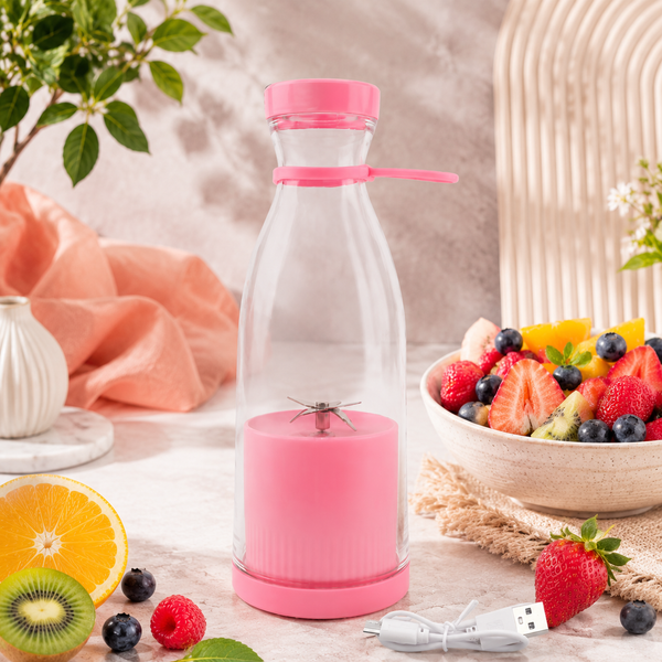 Pink portable blender bottle with a clear top and a bowl of fresh fruit beside it.