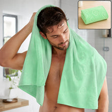 A man drying his hair with a light green microfiber towel in a bathroom, with a folded towel inset.