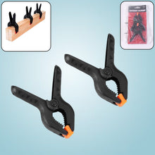 Close-up of a pair of heavy-duty spring clamps for mobile device screen repair.