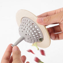 Hands holding a beige and grey silicone sink strainer basket, demonstrating how to empty collected food scraps.