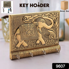 Close-up of the polished gold elephant head and hooks on the wooden key holder.