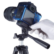 A gloved hand adjusts a blue camera mounted on a black and silver tripod against a white background.