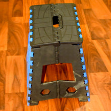 A person standing confidently on the 18-inch plastic step stool to reach a top kitchen cabinet.