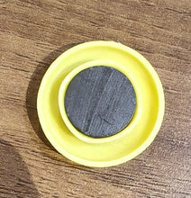 Yellow circular magnet placed next to pen for size reference