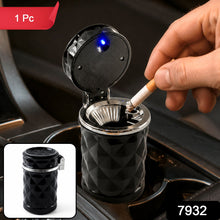 A hand places a lit cigarette into a black car cup holder ashtray with a blue LED light, with a red 