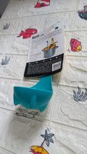 Multifunctional silicone soup spoon being used to strain vegetables from a pot.