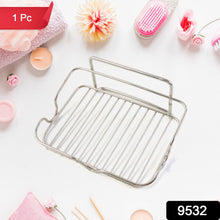A stainless steel wire soap dish is centered on a white surface surrounded by pink bath accessories.