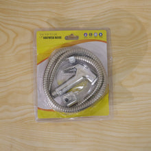 A packaged chrome bidet sprayer kit with a coiled hose is sealed in clear plastic on a light wooden surface.