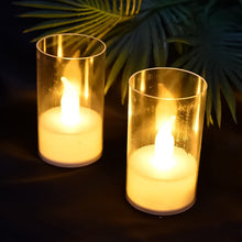 Two glowing LED flameless candles in transparent covers against a dark background with blurred green foliage.