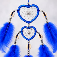 Close-up of the blue heart-shaped dream catcher, showing intricate web patterns, silver beads, and cowrie shells.