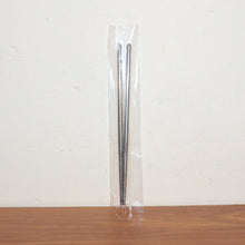 Stainless steel chopsticks actively used to pick up food during a meal.