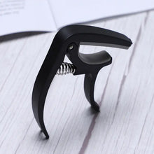 Guitar capo and pick holder positioned on a guitar neck, ready for playing.
