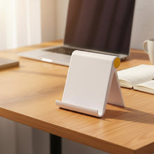 White foldable mobile phone holder positioned on a wooden desk