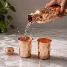 Front view of the diamond cut copper bottle and glasses, highlighting their reflective surface.