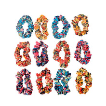 Displayed set of 12 printed fabric hair scrunchies on a flat surface