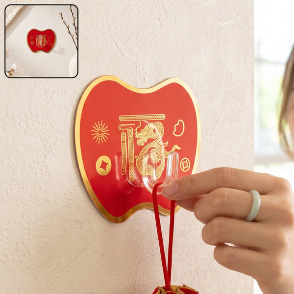 A hand hangs a red drawstring pouch on a red apple-shaped hook with gold Chinese characters and a dragon design.