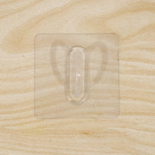 Close-up of transparent wall hook showing its adhesive pad