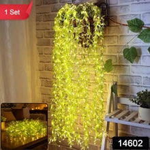 A hanging basket with long strands of green leaf string lights cascading down a brick wall, illuminated, with a red 