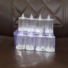 Eight clear ribbed LED flameless candles unlit, arranged on a brown quilted surface with a purple storage case.