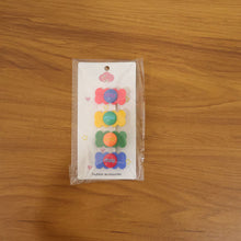 Hand holding a colorful candy hair clip showing its size and vibrant design