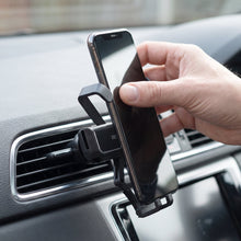 A hand removing a smartphone from a black car air vent phone holder attached to a car's vent.