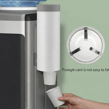 A white cup dispenser mounted next to a water cooler, with a hand taking a cup, and an inset showing the cup holder's
