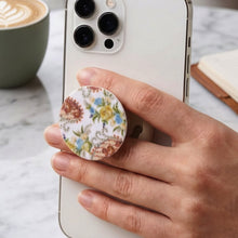 A hand holds a white smartphone with a round pop socket featuring a white background and colorful paisley floral – view 4