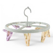 A light blue circular drying rack with purple and yellow clips is shown against a plain white background.