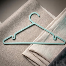 Plastic hanger holding shirt and dress, supporting heavy fabrics