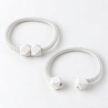 Two white braided rope curtain tiebacks with geometric white plastic fasteners on a plain white background.